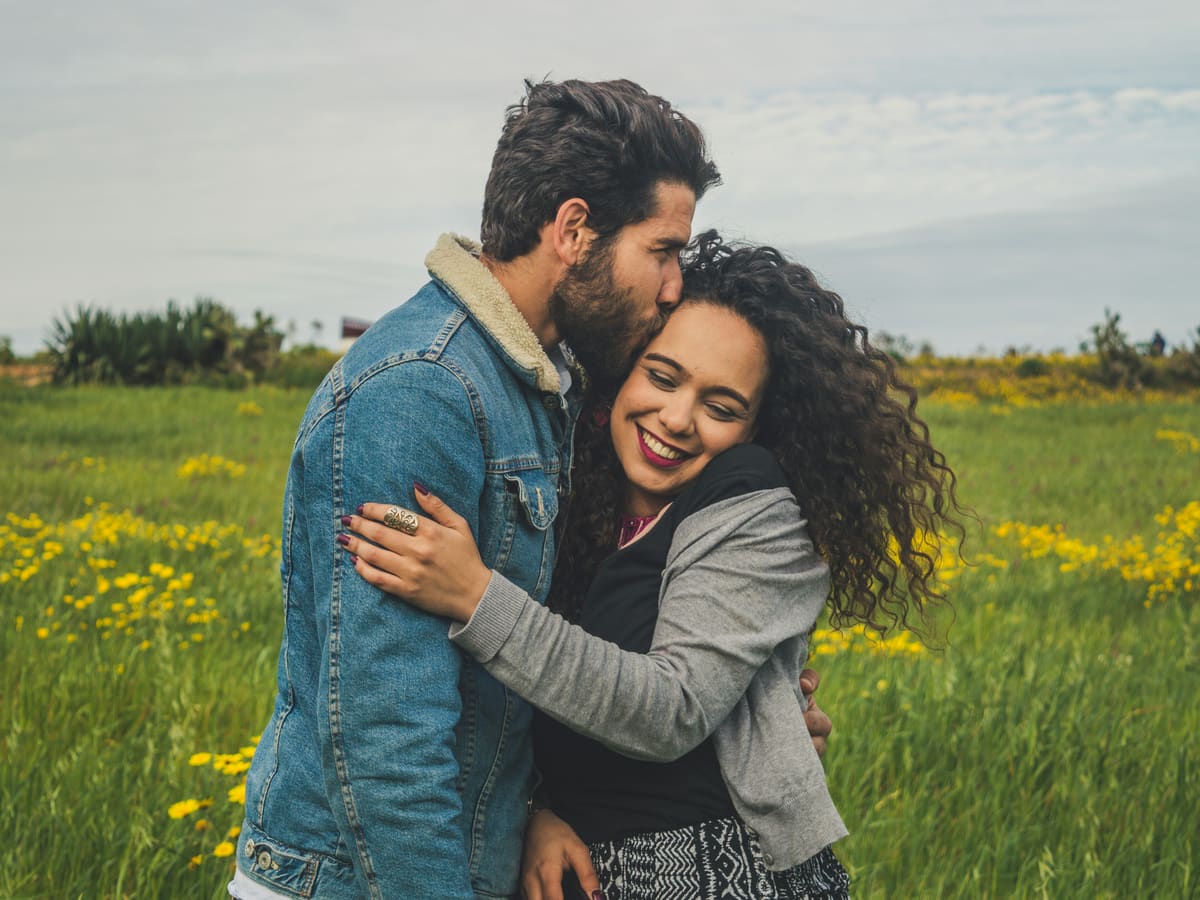 A couple holding each other close in a sunlit field